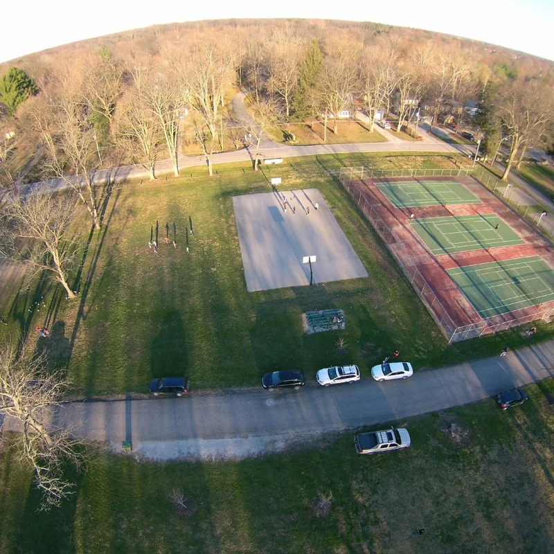 Tennis and basketball courts surrounded by green lawns and trees